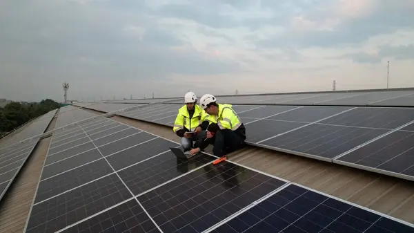 solar roof installation, Engineer with safety PPE and Harness install solar cells on the roof of the factory , green renewable energy