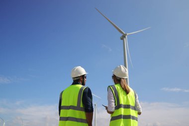 Bir çift elektrik mühendisi rüzgar türbini çiftliğinde birlikte çalışıyor..