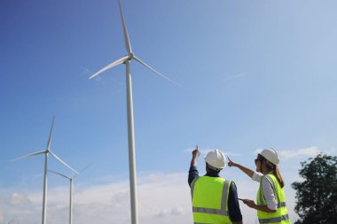 Bir çift elektrik mühendisi rüzgar türbini çiftliğinde birlikte çalışıyor..