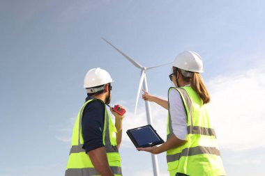 Bir çift elektrik mühendisi rüzgar türbini çiftliğinde birlikte çalışıyor..