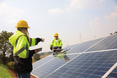 Gelecekteki elektrik üretimi. Erkek ve bayan meslektaşlar güneş panelleri, yeşil enerji ve yenilenme enerji kavramının açık havada çizimlerini okuyorlar