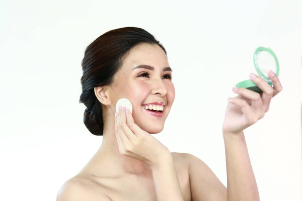 Красота портрет очаровательной азиатской женщины с красивым лицом здоровый цвет лица ухоженный тело мягко улыбается стоя с голыми плечами в помещении на белом фоне с чистой свежей кожей