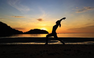 Kadınlar güzel gün doğumu ve gün batımına karşı sahilde yoga yaparlar. 