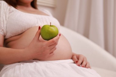 Hamile kadın evde bol meyve ve sebzeli sağlıklı yemek hazırlıyor.