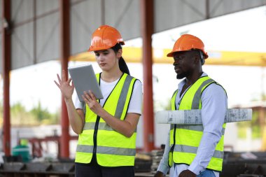 Kadın inşaat mühendisi, fabrikada meslektaşlarıyla birlikte çalışıyor.
