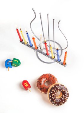 Yahudi bayramı Hanuka arkaplanı. Geleneksel yemek tatlı çörektir. Hanuka masası, mumlu şamdan ve beyaz arka planda dönen tepeler. En üstte İbranice alfabe harfleri. Boşluğu kopyala.