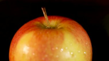 Olgun kırmızı elma ve siyah arkaplanda su damlaları var..