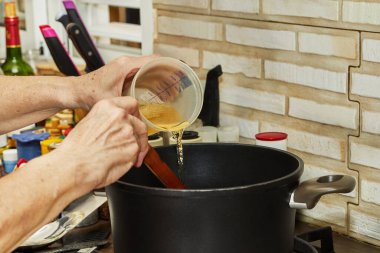 Şef mutfaktaki tencereye gaz sobasının üstünde sıvı döker..