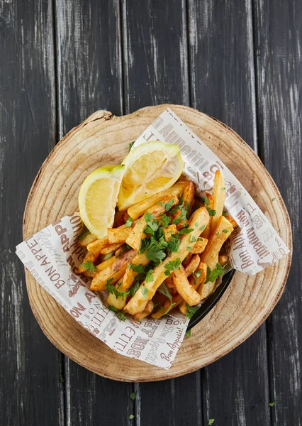 Stock image Potatoes with parsley and lemon, fried in oil on wooden board, serving in cafe. Flat lay