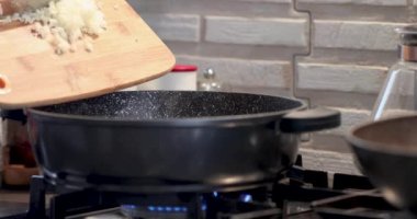 Aşçı turpları küçük parçalara ayırıp gaz sobasında kaynayan tavaya atıyor..