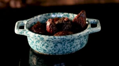 Cam kasede kurutulmuş incir ve siyah arka planda ışık..