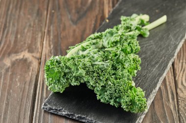 Ahşap zeminde siyah taşın üzerinde kıvrılmış marul..