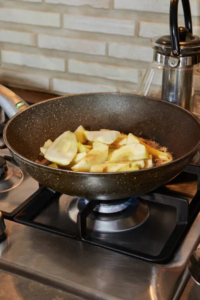 Frying pan on gas stove on fire with pears in syrup.
