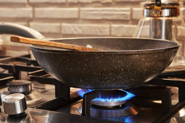 Frying pan on gas stove on fire with dish being prepared.