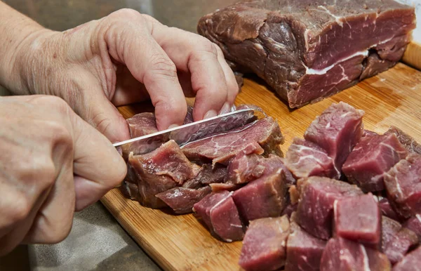 Chef cuts the beef meat into cubes for cooking.