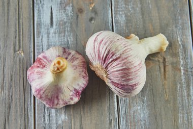 Fresh bulbs of garlic stacked on wooden gray background.