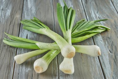 Fresh leek stacked on wooden gray background. Close up.