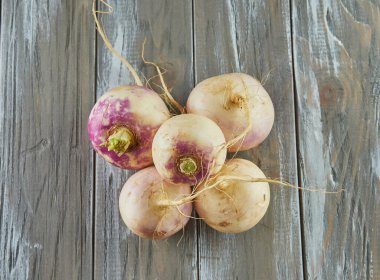 Fresh purple turnip stacked on wooden gray background.