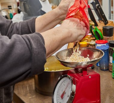 Şef ev mutfağındaki parmesan peynirini tartıyor..