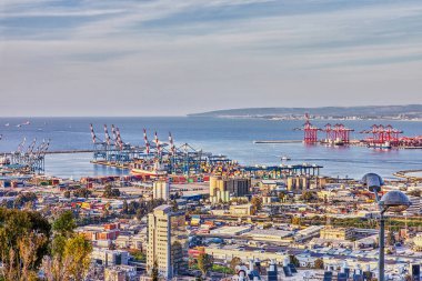 Sea port in the city of Haifa, panorama of the port and city buildings against blue sky with clouds. clipart