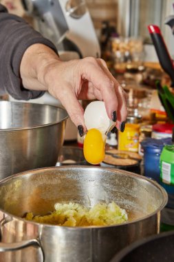 Chef cracks an egg into dish that is being prepared in bowl.