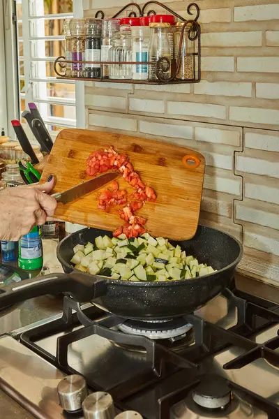 stock image Chef adds chopped tomatoes to the pot with the ingredients on the gas stove.