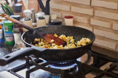 Kavrulmuş domates ve patlıcan, gaz sobasında malzemelerle karıştırılmış..