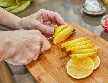 Citrus Zest: Yetenekli Şef, Vibrant Kitchen 'ın taşralı ahşap tahtasında taze limon halkaları dilimliyor.