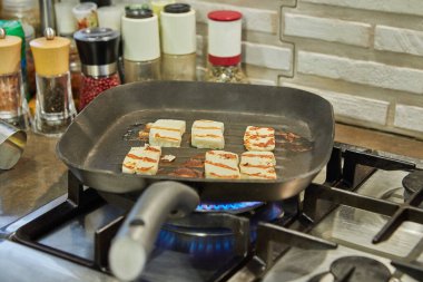 Halloumi peyniri tavada kızarır ocağın üstünde..