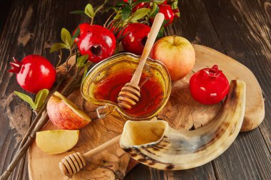 Rosh hashanah - jewish new year holiday concept. Bowl in the shape of an apple with honey, apples, pomegranates, shofar on wooden vintage background.
