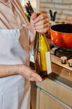 Şef mutfakta bir şişe beyaz şarap tutuyor..