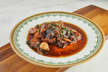 Sarımsaklı Ossobuco ve süslemeli kırmızı şaraplı yeşil soğan..