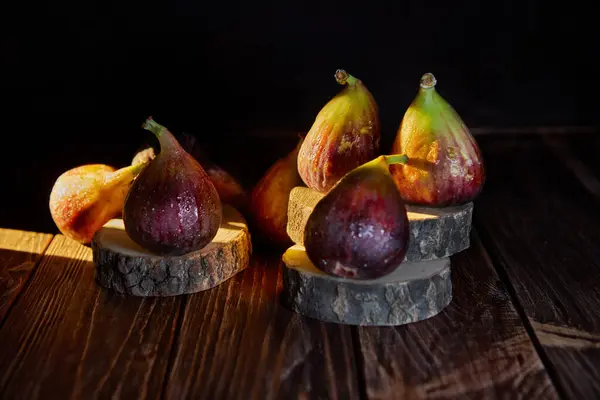 Figs on wooden background and wooden stands with hard shadows.