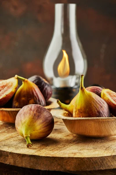 Figs on wooden background and wooden stand with an old lamp with fire.