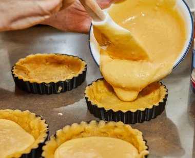 Vişneli turta yapmak için hamuru küçük yuvarlak kalıplara dökün.