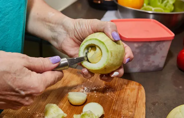 Chef cuts out the inside of zucchini for stuffing in home kitchen.