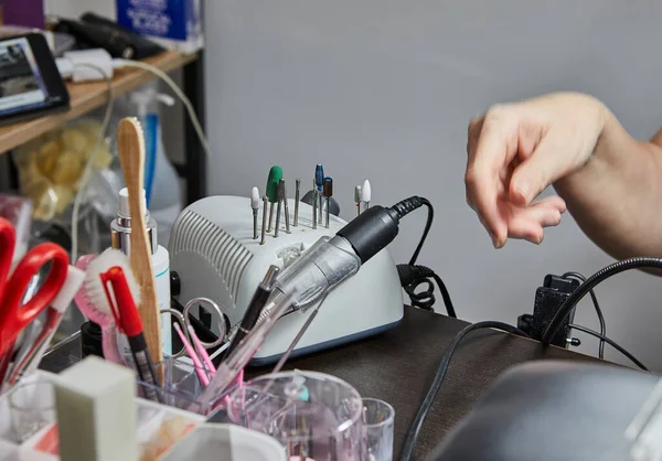 Skilled nail technician providing gel nail extension and perfect polish during a manicure salon service. Close-up of the hands and nails with professional tools and products.