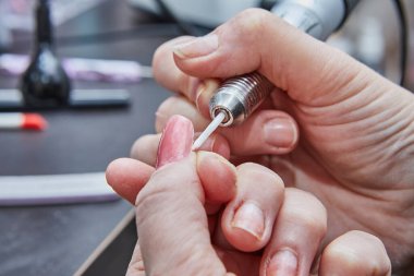 Bir tırnak teknisyeninin ustalıkla jöle sürme, tırnakları ustalıkla cilalama ve baş döndürücü ve kusursuz el tırnakları yapmak için manikür makinesi kullanma uzmanlığına tanık olun..