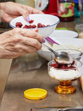 Şefin elleri bardakta lezzetli bir tatlı yapıyor, taze krema, sulu kirazlar, çıtır çıtır kurabiyeler ve fındıklar, enfes mutfak becerileri ve detaylara dikkat..