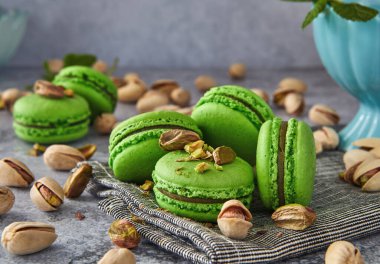 Lezzetli şam fıstığı aromalı makaronlar, taze nane yapraklarıyla süslenmiş, eski, gri ahşap bir arka planda güzelce düzenlenmiş. Şekerlemeler, tatlı ya da yemek blogu içeriği için mükemmel görüntü.