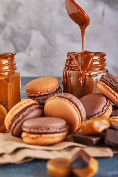 Chocolate macarons with caramel sauce, chocolate, and caramel candy on brown paper. Perfect for food and cooking magazines, websites, blogs, and ads for chocolate products.
