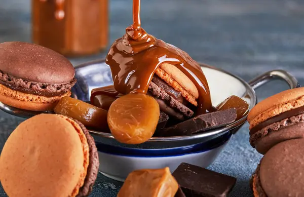 Chocolate macarons with caramel sauce, chocolate, and caramel candy on brown paper. Perfect for food and cooking magazines, websites, blogs, and ads for chocolate products.