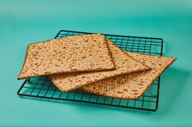 Hamursuz bayramı konsepti, Yahudi bayramı. Mavi arka planda bir yığın matzo. Metal bir ızgarada güzel bir kompozisyon..
