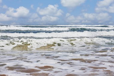 Deniz kıyısı ve dalgalar bulutlu bir gökyüzünün arka planında.