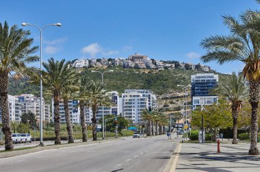 Hayfa, İsrail 6 Nisan 2024: Hayfa 'da şehir sokağı palmiye ağaçları, binalar ve sokak lambaları bulutlu bir gökyüzünün altında.