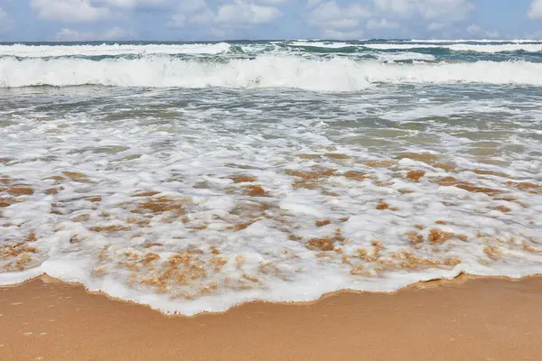 stock image Seashore with rolling waves against the background of a sky with clouds.