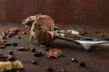 Kahverengi beton arka planda yuvarlanan toplar için özel metal kaşıkta çikolatalı dondurma..