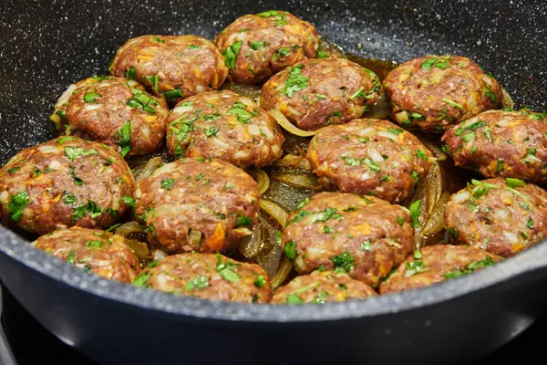 stock image Frying pan with meat cutlets with seasonings on an electric stove in a home kitchen. Close-up.