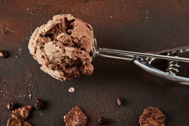 Kahverengi beton arka planda yuvarlanan toplar için özel metal kaşıkta çikolatalı dondurma. Düz yatıyordu. Boşluğu kopyala