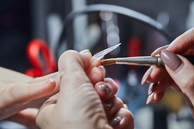 Bir manikürcü, güzellik salonunda tırnaklarını titizlikle törpülüyor. Detaylı tırnak bakımı ve sanat eserleri sergiliyor..